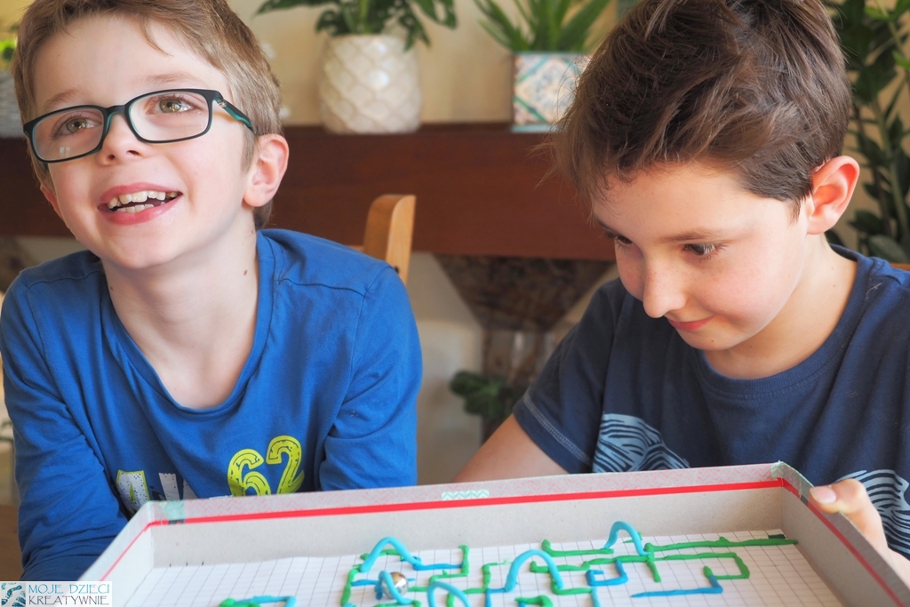 dzieci bawią się w kodowanie bez komputera, trzymają pudełko z labiryntem z plasteliny
